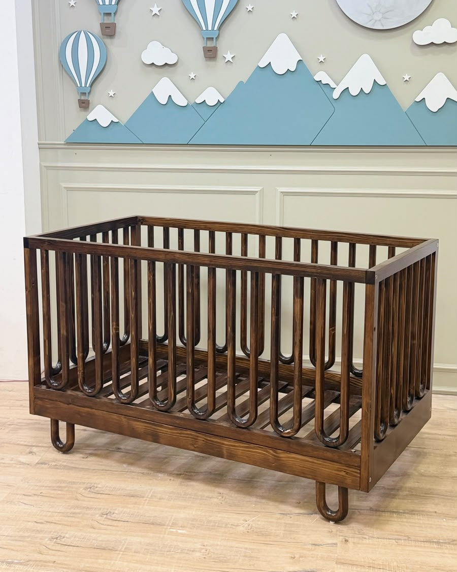 A dark brown wooden convertible crib with a slatted guard.